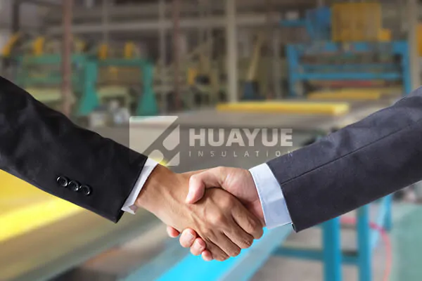A handshake between diverse business professionals with a HUAYUE factory in the background