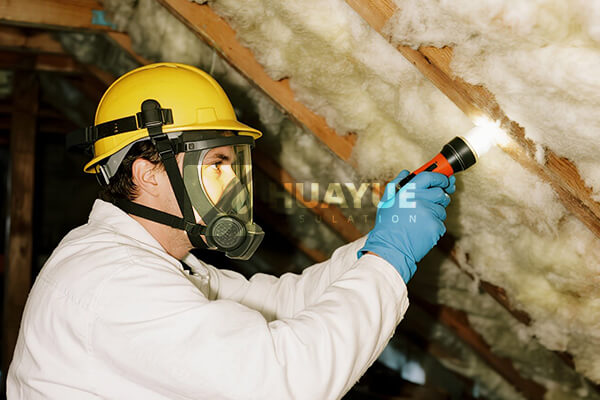 A professional checking fiberglass insulation in an attic