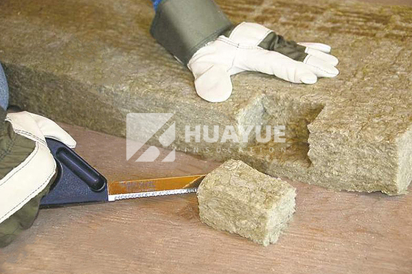 Rock wool board being handled with gloves and long sleeves
